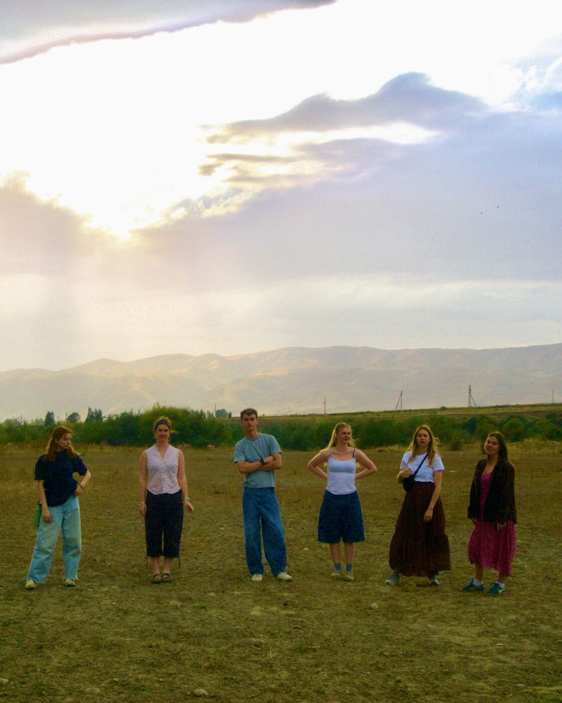 A group of friends in a field at sunset